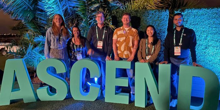 Reflecting on ascend 2024: resolver security summit 5 The resolver customer success team posing in front of the illuminated 'ascend' letters at ascend 2024, with a backdrop of palm trees and blue lighting.