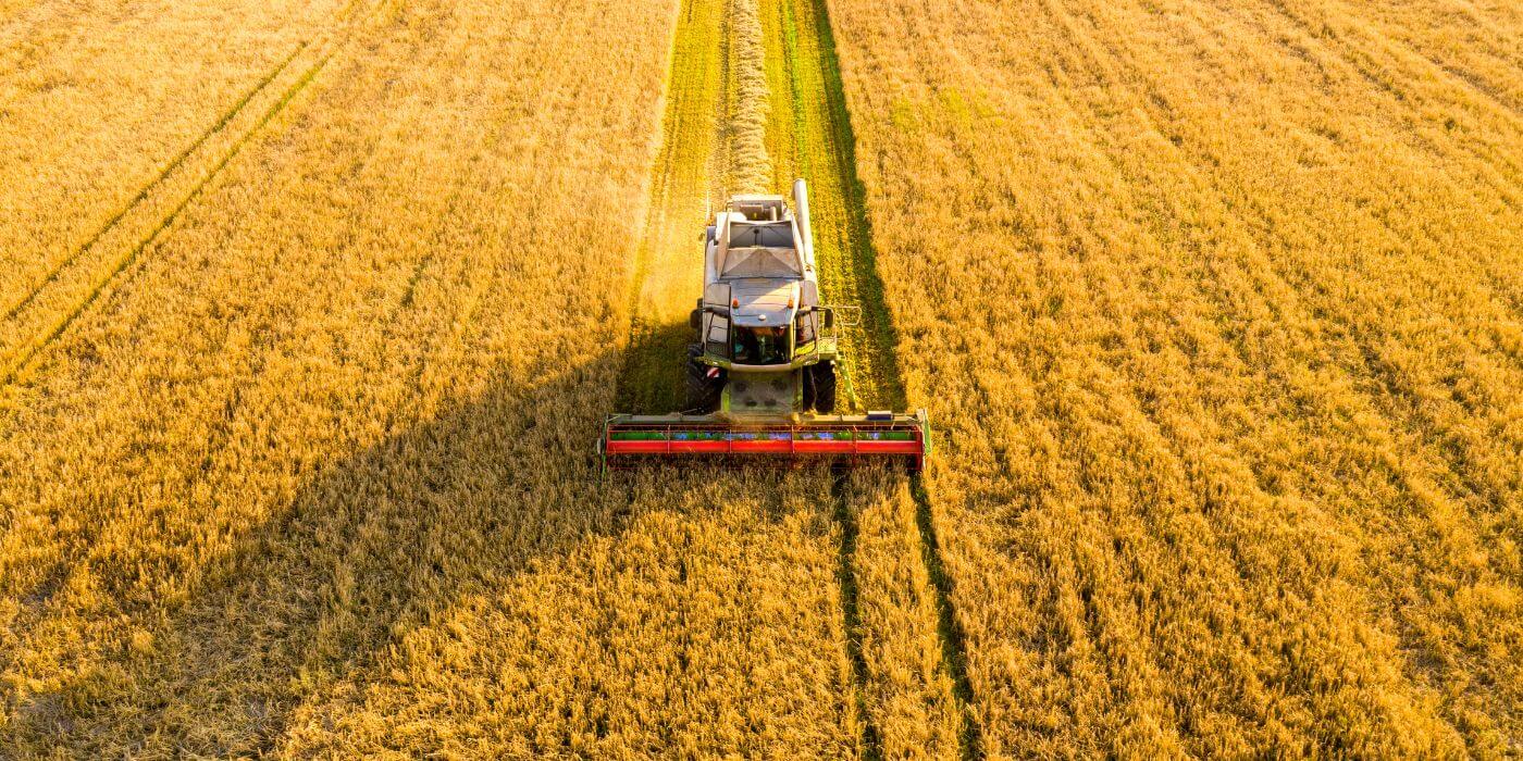 Image of tractor going through yellow field representing global agricultural manufacturer