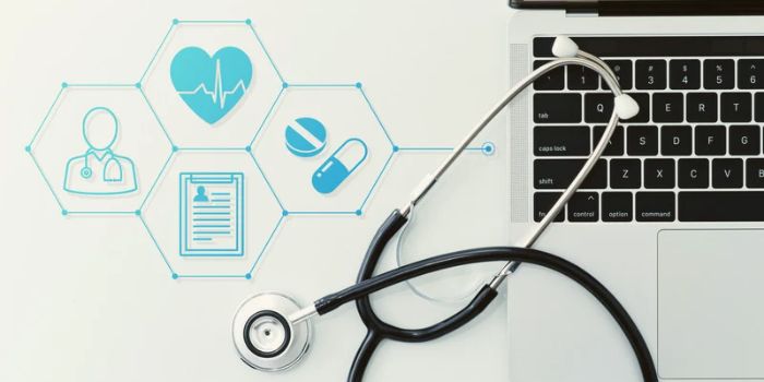 Laptop with stethoscope over keyboard with digital icons representing regulatory compliance in healthcare