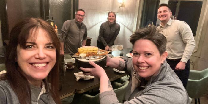 A group of resolver team members at a dinner, smiling and enjoying themselves. One team member holds a dish, indicating a moment of celebration or fun during a team bonding event at isc west 2024.