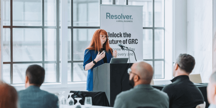 Key insights from resolver's grc day 2024 5 Ux research lead, sydney lamorea, at a podium for resolver's grc day, speaking to a crowd with a banner behind her reading "unlock the future of grc. "