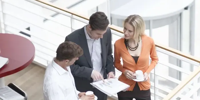 One man standing between another man and woman, holding papers while explaining information representing effective grc program